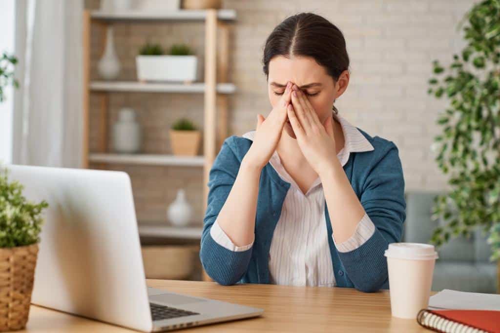 woman at laptop rubs her sore eyes - is it digital eye strain